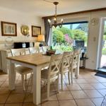 Dining room with wooden table, white chairs, and view of garden
