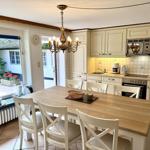 Kitchen with dining table, white chairs, and view to balcony.
