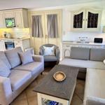 Living and kitchen area with sofa, armchair, and kitchenette.