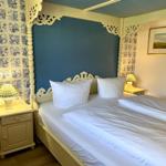 Bedroom with bed, nightstands, and wall covering with motifs.
