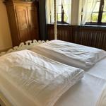 Bedroom with double bed, wooden wardrobe, and window with view of greenery.