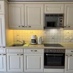 Kitchen with white cabinets, stove, microwave, and coffee maker.