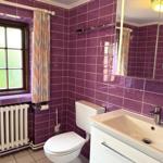 Bathroom with purple tiles, sink, toilet, and window.