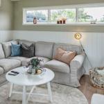 Living room with corner sofa, round table, and windows overlooking outside.