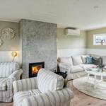 Living room with sofa, chairs, fireplace, and window. Wall decor and rug.