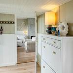 Entryway with cabinet, lamp, and decor. View into living room with seating.