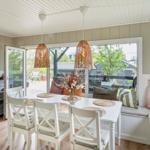 Dining room with white table, chairs, and window seat with cushions.