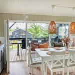 Dining room with white table, chairs, and bench. Entrance to terrace with garden view.