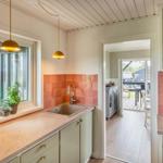 Kitchen with worktop, sink, and window. Passage to living area with terrace.