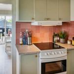 Kitchen with induction cooktop, wooden surfaces, and pink tiles on the wall.
