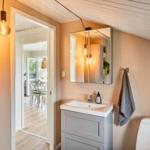 Bathroom with sink, mirror, and toilet. Corridor to kitchen with table and chairs.