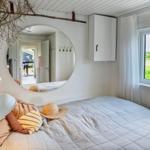 Bedroom with bed, wall mirror, and window view of green field.