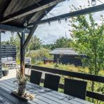 Terrace with table, chairs, and string lights. View of green trees and neighboring houses.