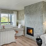 Living room with fireplace, seating, and view of green hills.