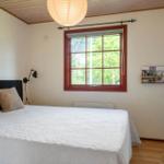 Bedroom with bed, window, and dresser. Wooden ceiling, lamp, and wall mount.