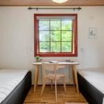 Room with two beds, desk, and window with view of green.
