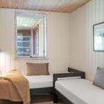 Two single beds in a room with wood paneling and a window.