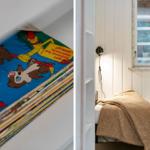 Bedroom with bed, blanket, and window. Shelf with comics.