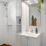 Shower, sink, and mirror cabinet in white bathroom fixtures.