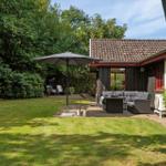 Backyard with garden, seating area, and umbrella next to a house with red windows.