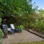 Two lounge chairs are on a paved area in the greenery.