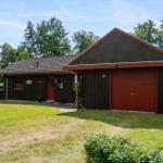 A house with a red garage and dark facade. Lawn and trees surround the building.