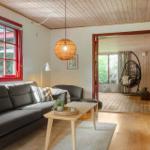 Living room with gray sofa, red window, and wooden ceiling. Entrance to terrace with hanging chair.