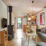 Living area with sofa, dining table, and wood stove. Kitchen and bedroom are visible.