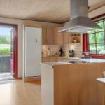 Kitchen with wooden surfaces, white cabinets, and red window frames. Entrance to the terrace.