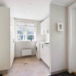 Laundry room with washing machine, windows, and white cabinets.