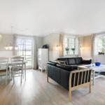 Living and dining area with sofa, table and chairs. Large windows with view of garden.