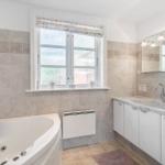 Bathroom with bathtub, sink, and window.