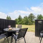 Terrace with table, chairs, and grill. View of green lawn and trees.