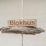 A wooden sign reading Blokhus hangs on a rope.