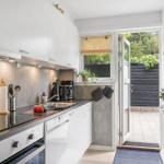 Kitchen with white cabinets, dark countertop, and view to the garden.