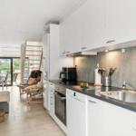 Kitchen with white cabinets, stainless steel sink, and view into living area.