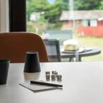 Table with dice, cup, and pen in front of window with garden view.