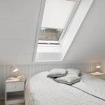 Bedroom with skylight, bed, nightstands, and wall-mounted TV.