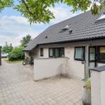 House with terrace, garden, and bicycle. Roof with skylights. Paved path and greenery.