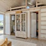 Living area with dining space, cabinet, toilet, and loft area with ladder.