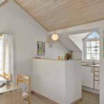 Kitchen with dining area under wooden ceiling, windows, wall art, and kitchen counter.