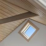Skylight in a room with wooden ceiling and white walls.