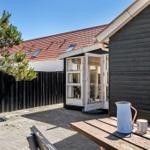 Terrace with table, kettle, and mug. Backyard with wooden wall and window.