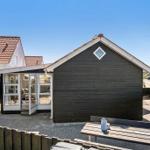 Wooden house with terrace and seating. Glass door leads to interior.