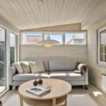 Living area with sofa, round table, and wood walls. Large windows and skylight.