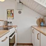 Kitchen with wooden surfaces, white cabinets, and sloped ceiling.