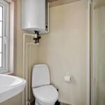 Bathroom with toilet, shower, and sink under window.