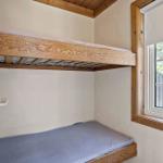 Room with bunk bed and window with wooden frame.