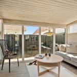 Living area with sofa, table, and chair. Large windows offer view of the garden.
