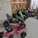 Mehrere Kinderkarts stehen in einer Garage mit Steinwand und Holztür.